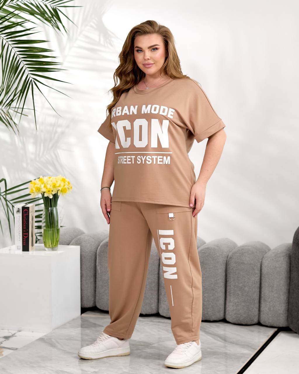 Woman wearing a beige 'Urban Mode Icon' outfit in a living room setting.