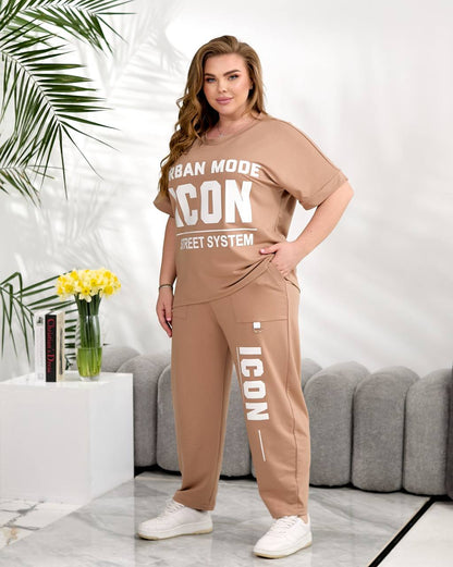 Woman wearing a beige tracksuit with 'ICON' branding in a modern living room.