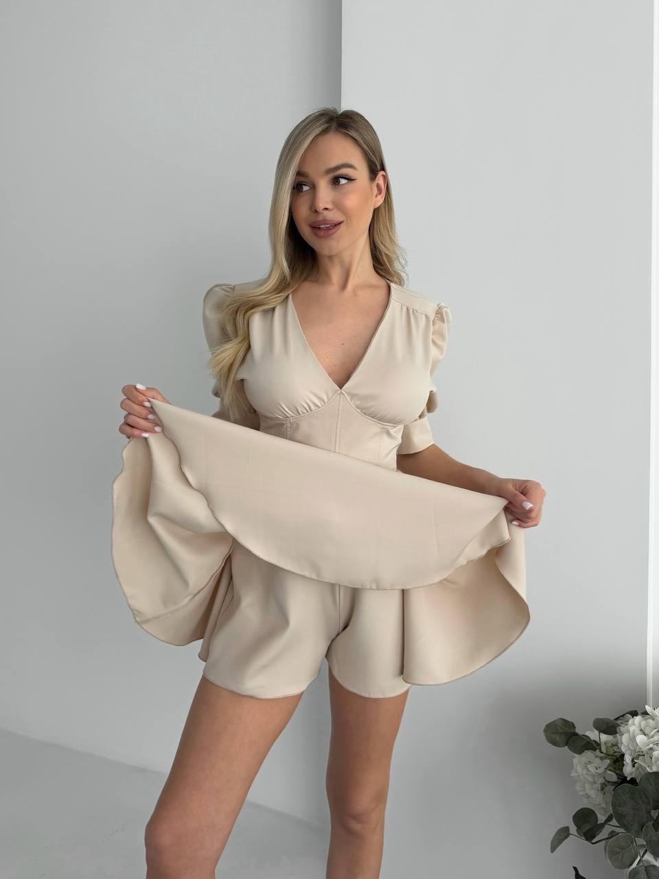 Woman wearing a beige dress with puffed sleeves against a plain background