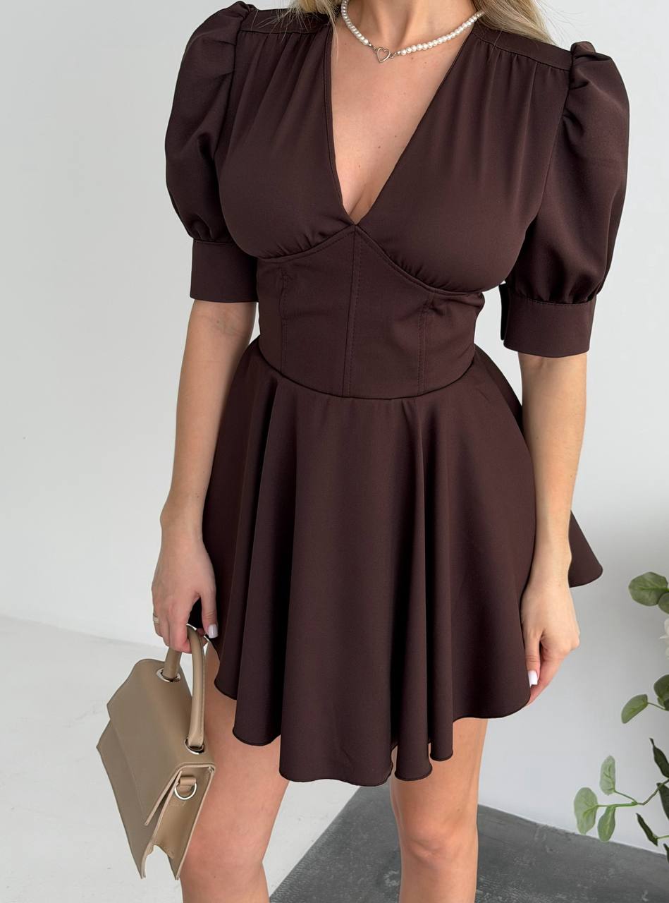 Woman wearing a brown dress with puff sleeves against a neutral background