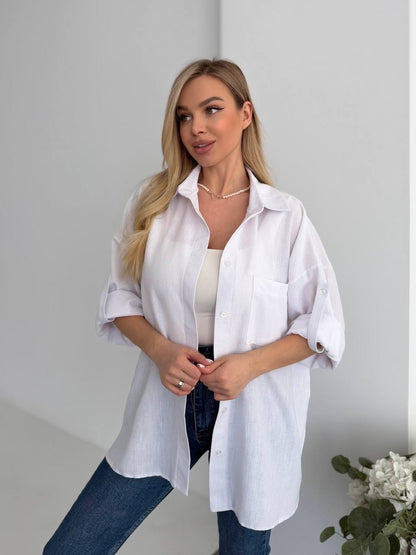 Woman wearing a white shirt and blue jeans against a plain background