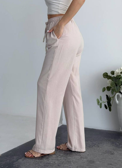 Person wearing light pink wide-leg pants with a neutral background