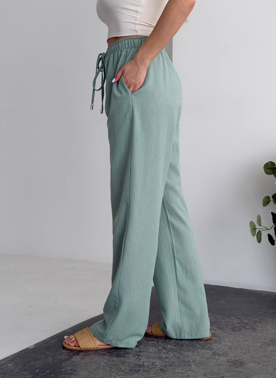 Person wearing light green wide-leg pants on a neutral background