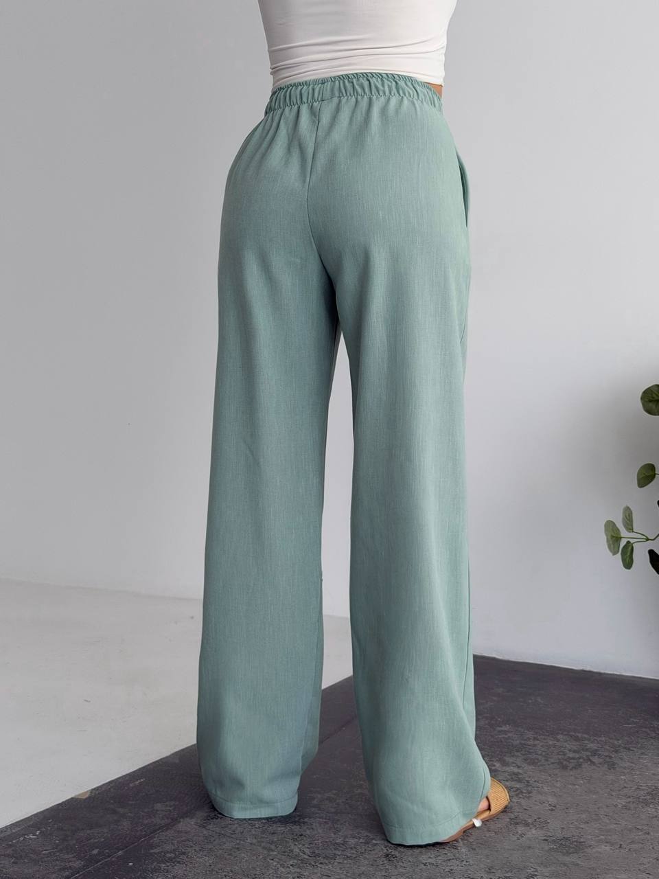 Teal wide-leg pants worn by a person on a neutral background