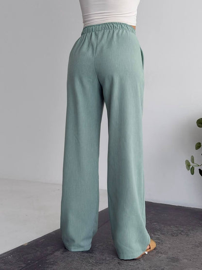 Teal wide-leg pants worn by a person on a neutral background