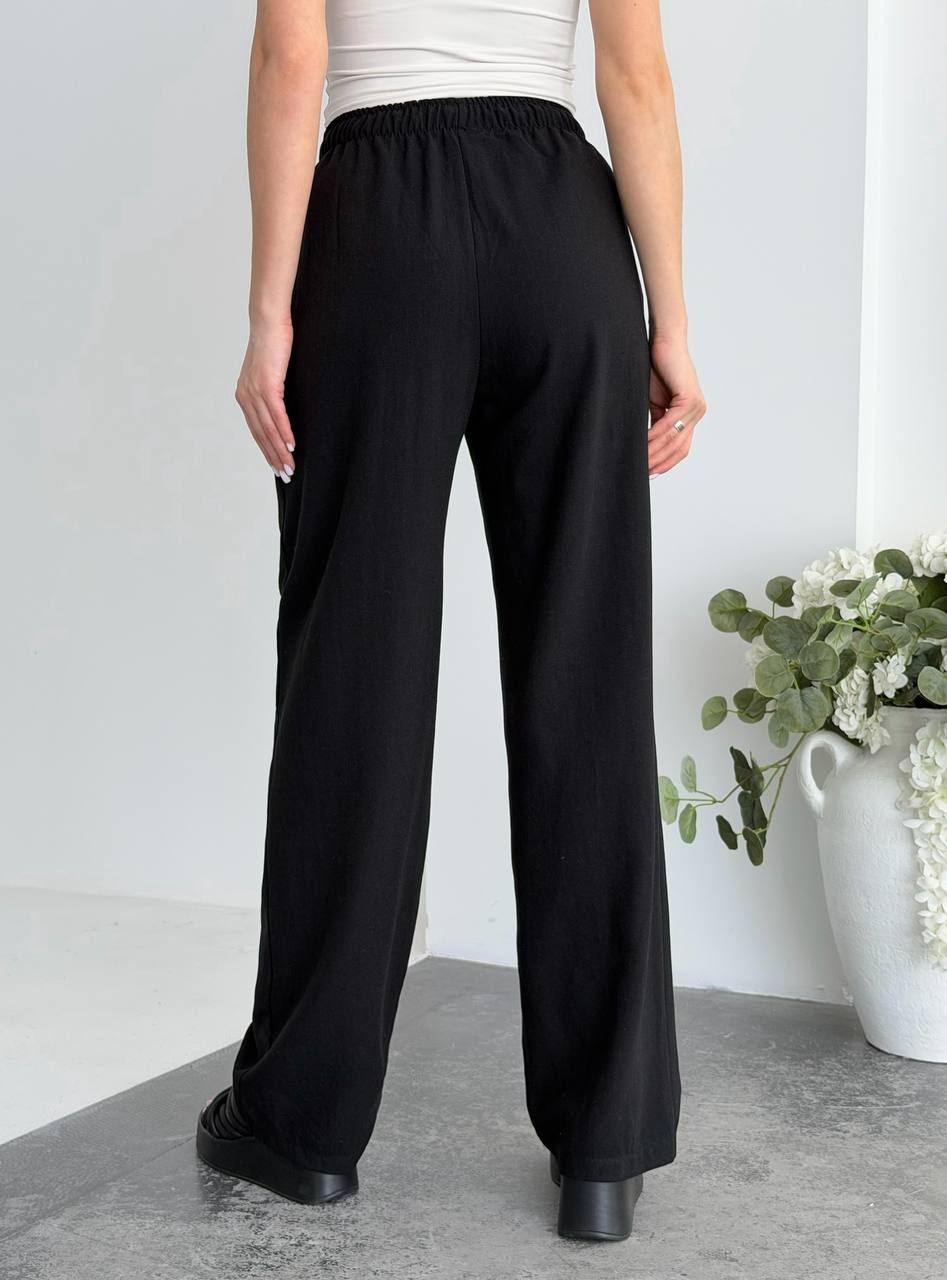 Person wearing black wide-leg pants with a white background
