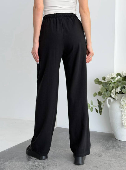 Person wearing black wide-leg pants with a white background