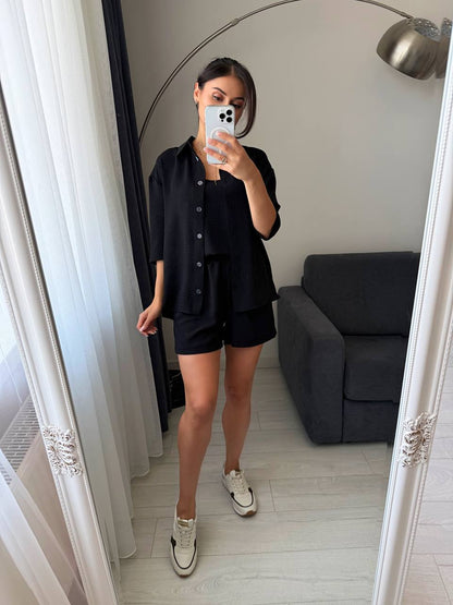 Person taking a mirror selfie wearing a black outfit in a room with a gray sofa.