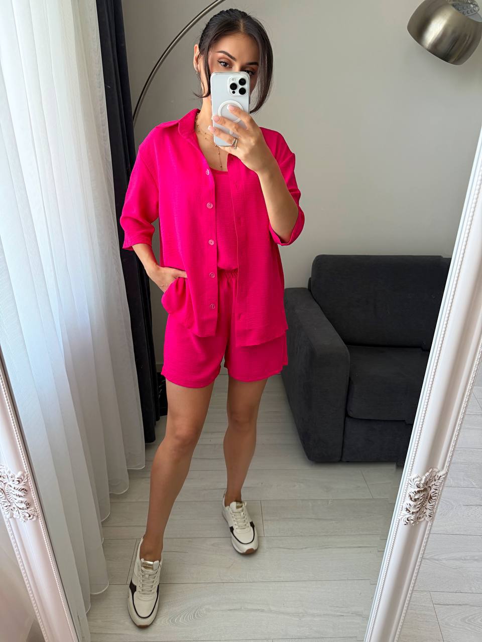 Person wearing a bright pink outfit taking a mirror selfie in a room.
