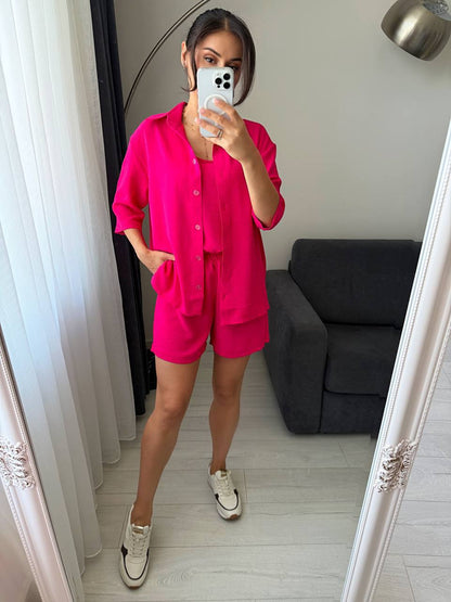 Person wearing a bright pink outfit taking a mirror selfie in a room.
