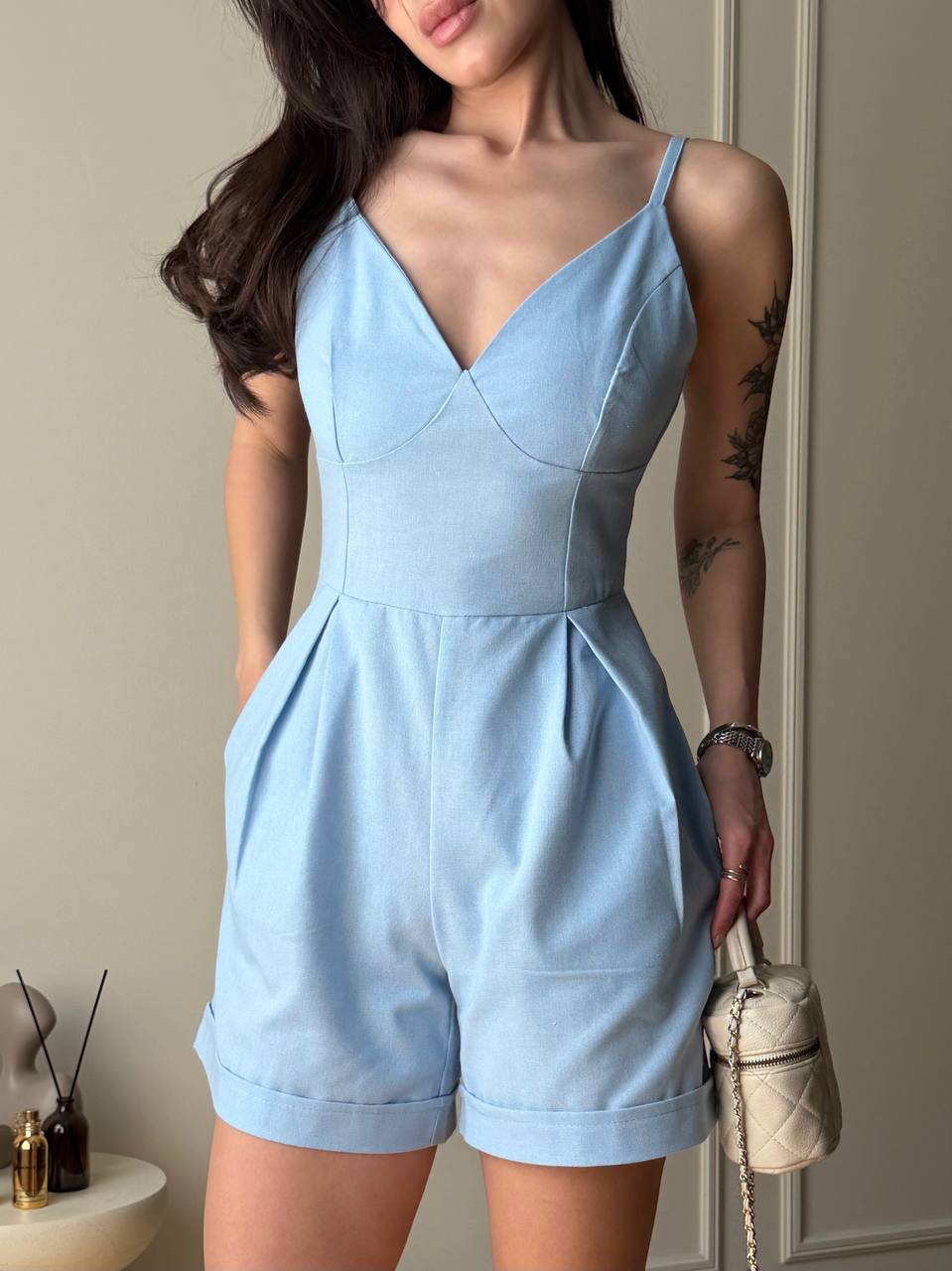 Woman wearing a light blue romper with a neutral background