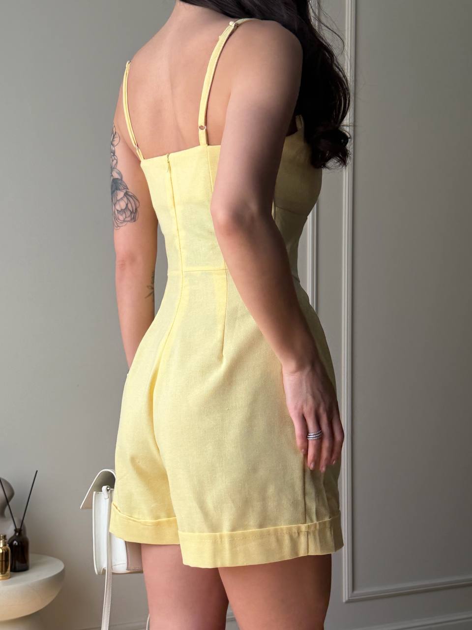 Person wearing a yellow dress standing against a neutral wall.