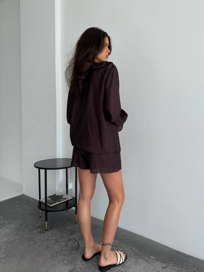 Woman in a dark outfit standing in a minimalistic room with a small round table.