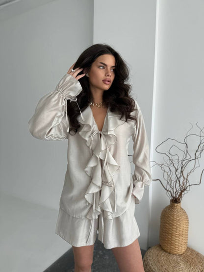 Woman wearing a satin pajama set in a minimalistic room.