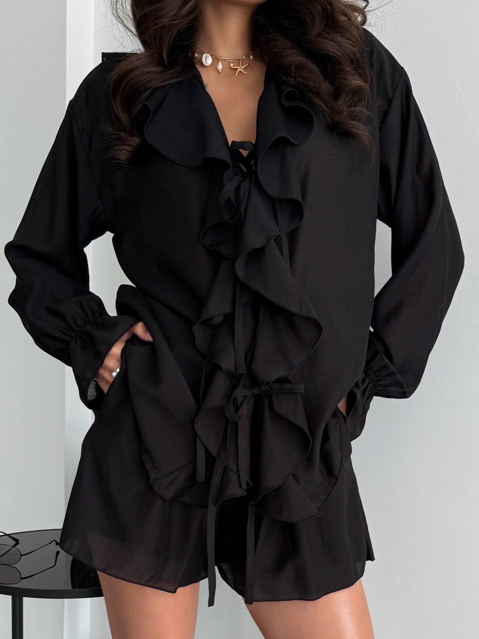 Black ruffled outfit worn by a person against a white background