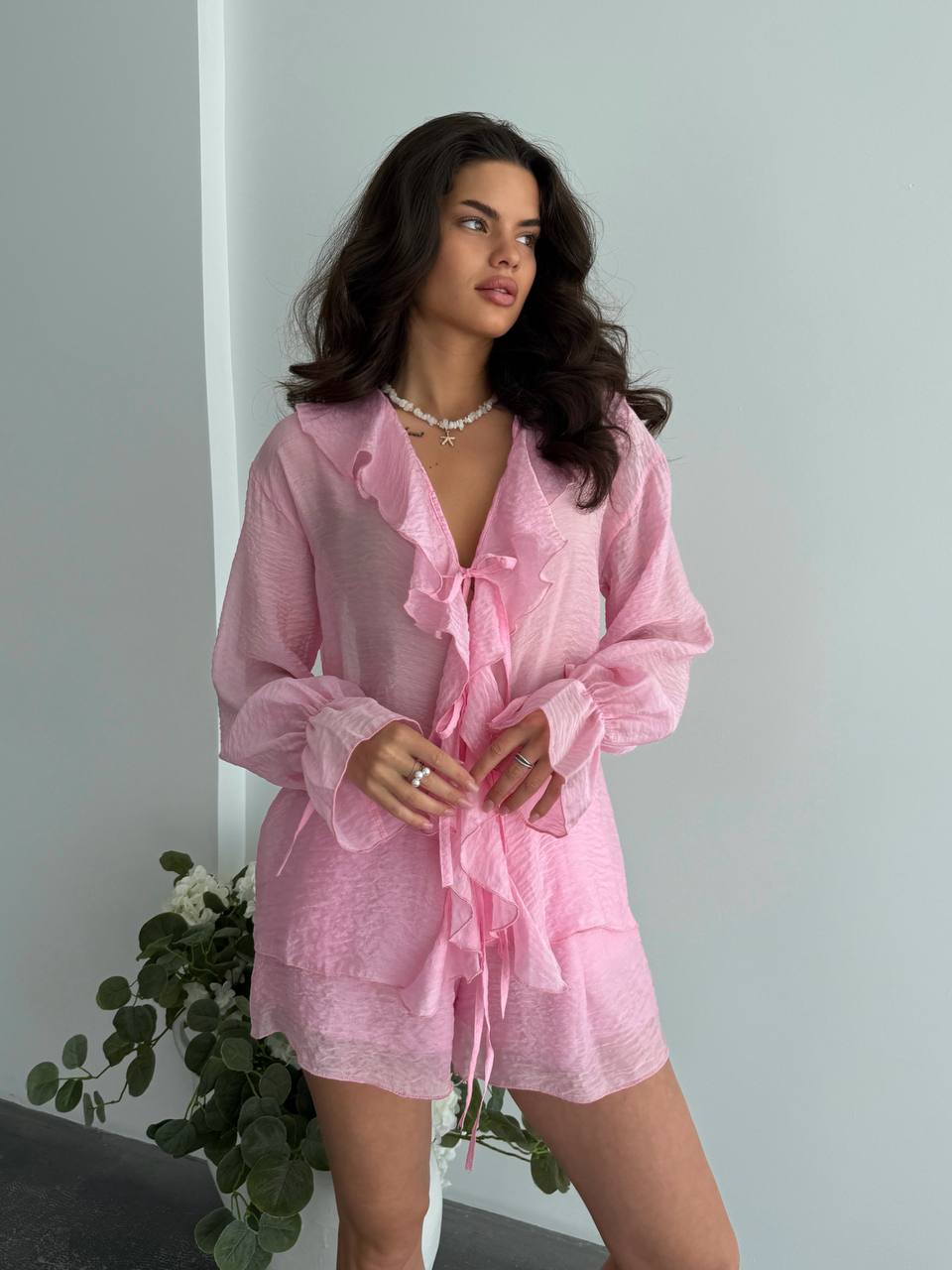 Woman wearing a pink lace outfit against a plain background