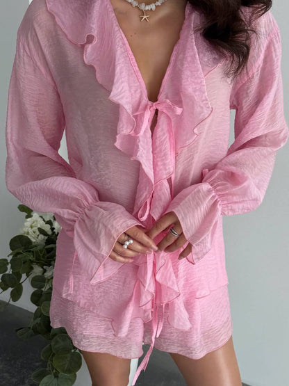 Person wearing a pink robe with ruffled details against a neutral background