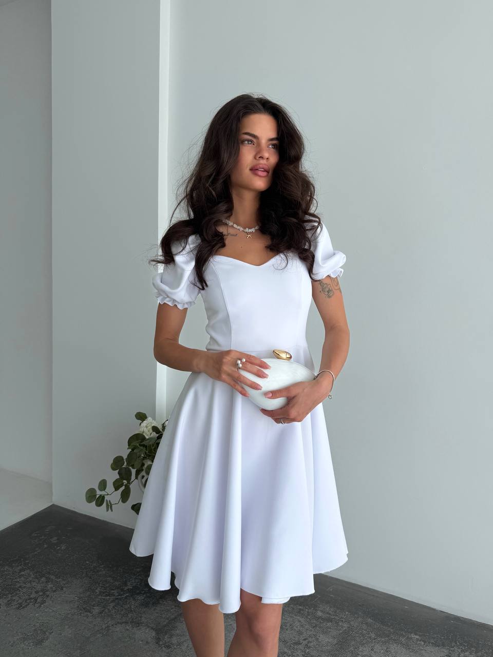Woman wearing a white dress holding a white bowl against a plain background