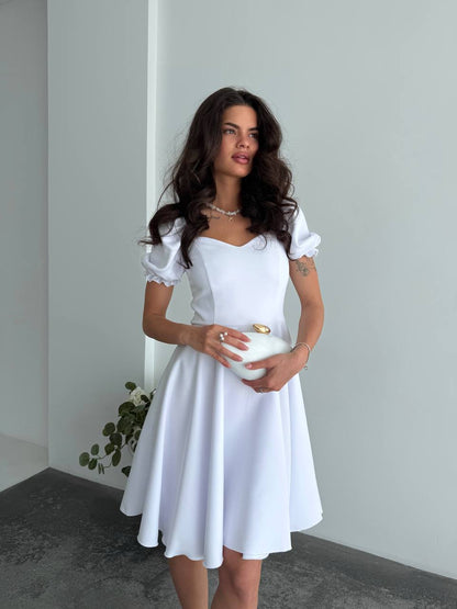Woman wearing a white dress holding a white bowl against a plain background