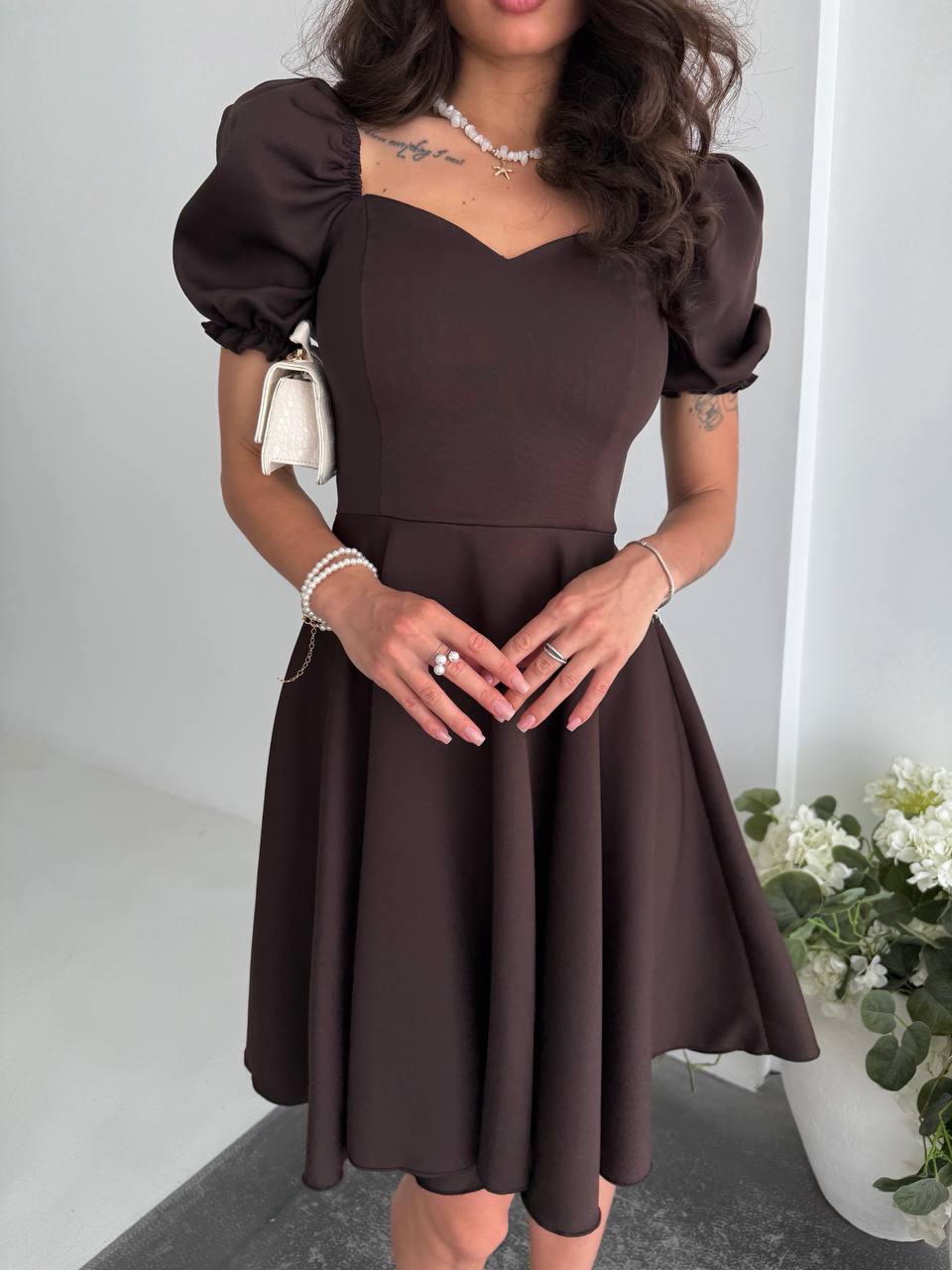 Woman wearing a brown dress with puffed sleeves in an indoor setting.
