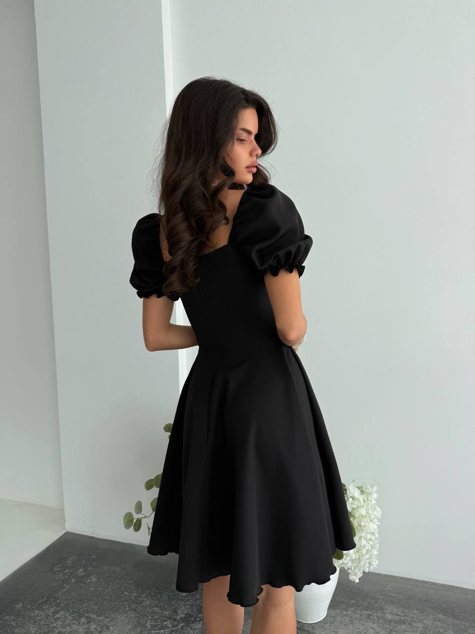 Woman wearing a black dress with puffed sleeves against a white background