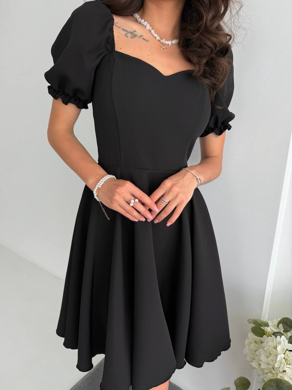 Black dress with puffed sleeves worn by a person on a white background