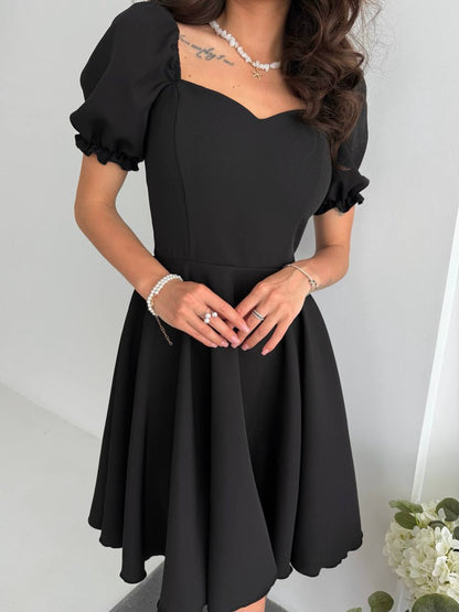 Black dress with puffed sleeves worn by a person on a white background