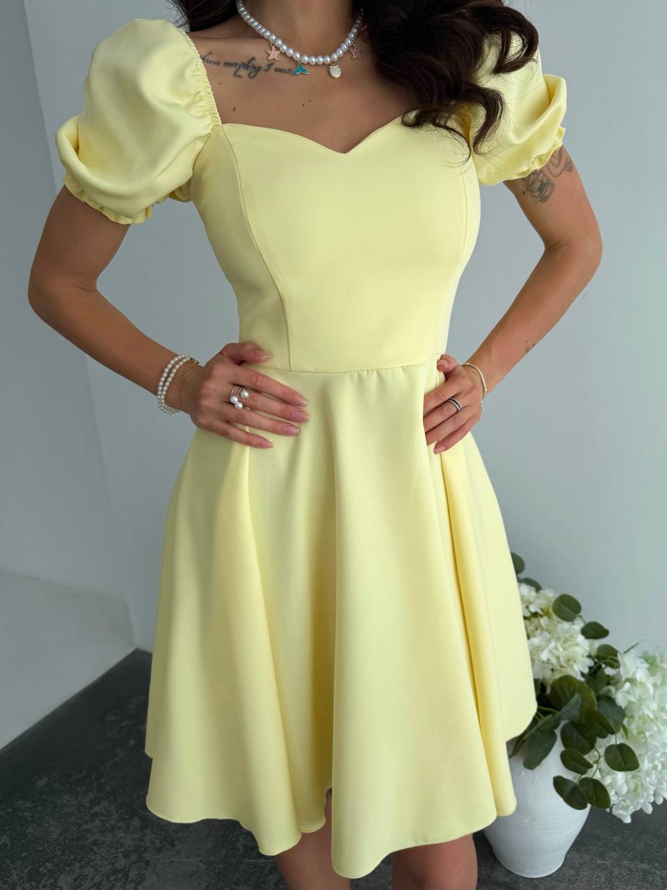 Woman wearing a yellow dress with puffed sleeves against a neutral background