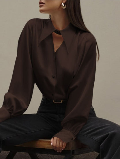 Woman wearing a dark brown blouse and black pants sitting on a wooden stool against a neutral background