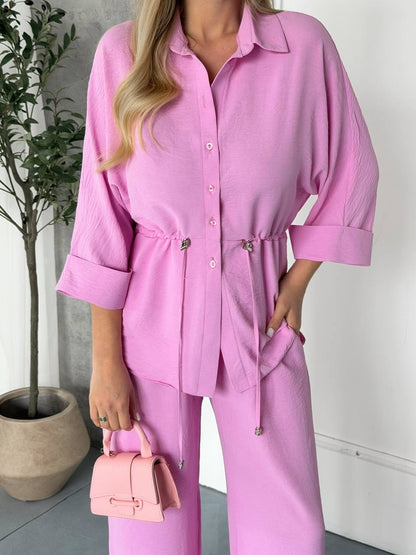 Person wearing a pink outfit with a matching handbag indoors.