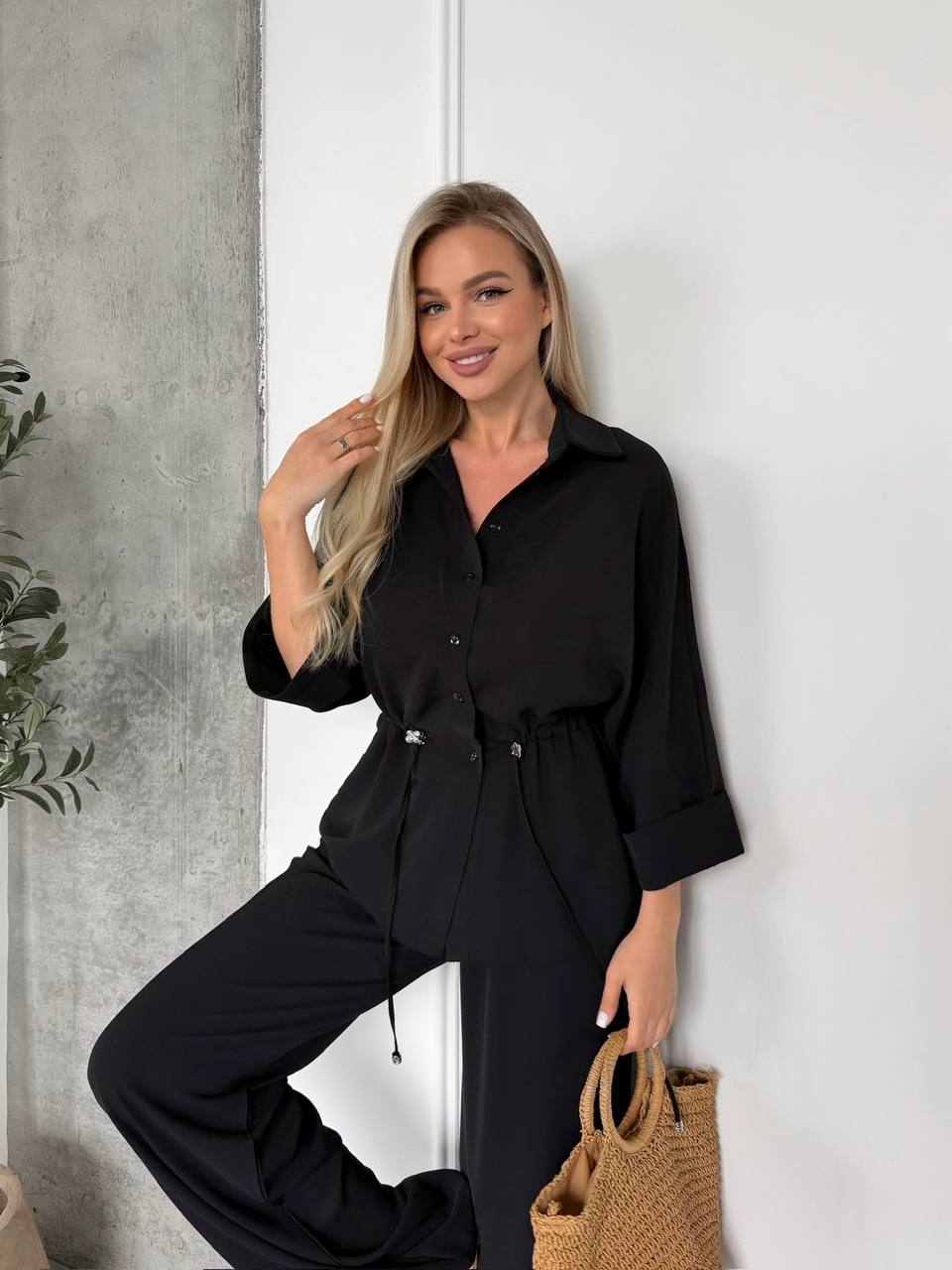 Woman wearing a black outfit against a white wall