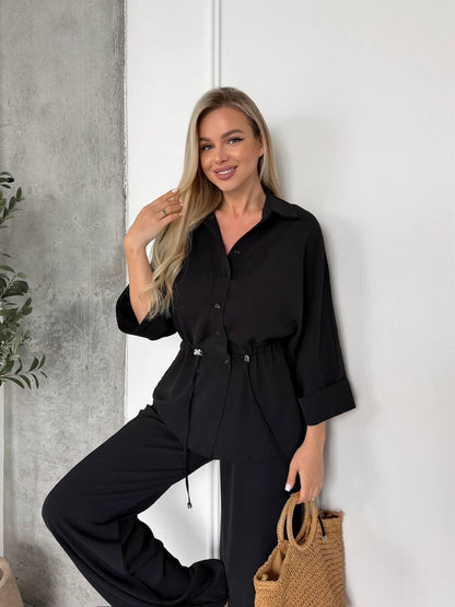 Woman wearing a black outfit against a white wall