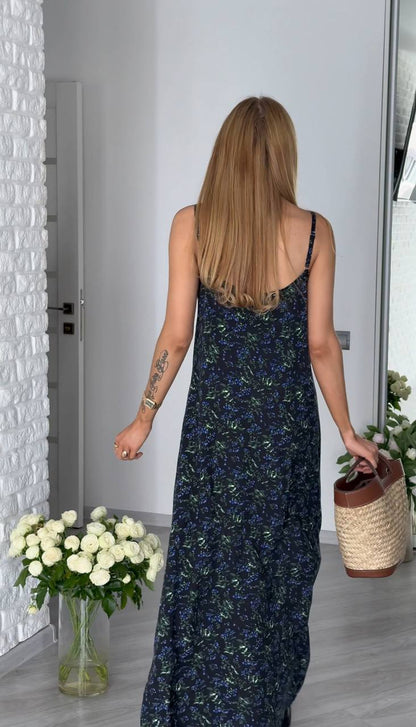 Woman in a floral dress walking away from the camera with a vase of flowers and a basket.