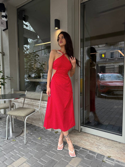 Woman in a red dress standing outside a building with a reflective surface.