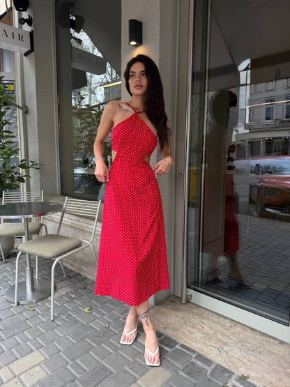 Woman in a red dress standing outside a store with glass doors.