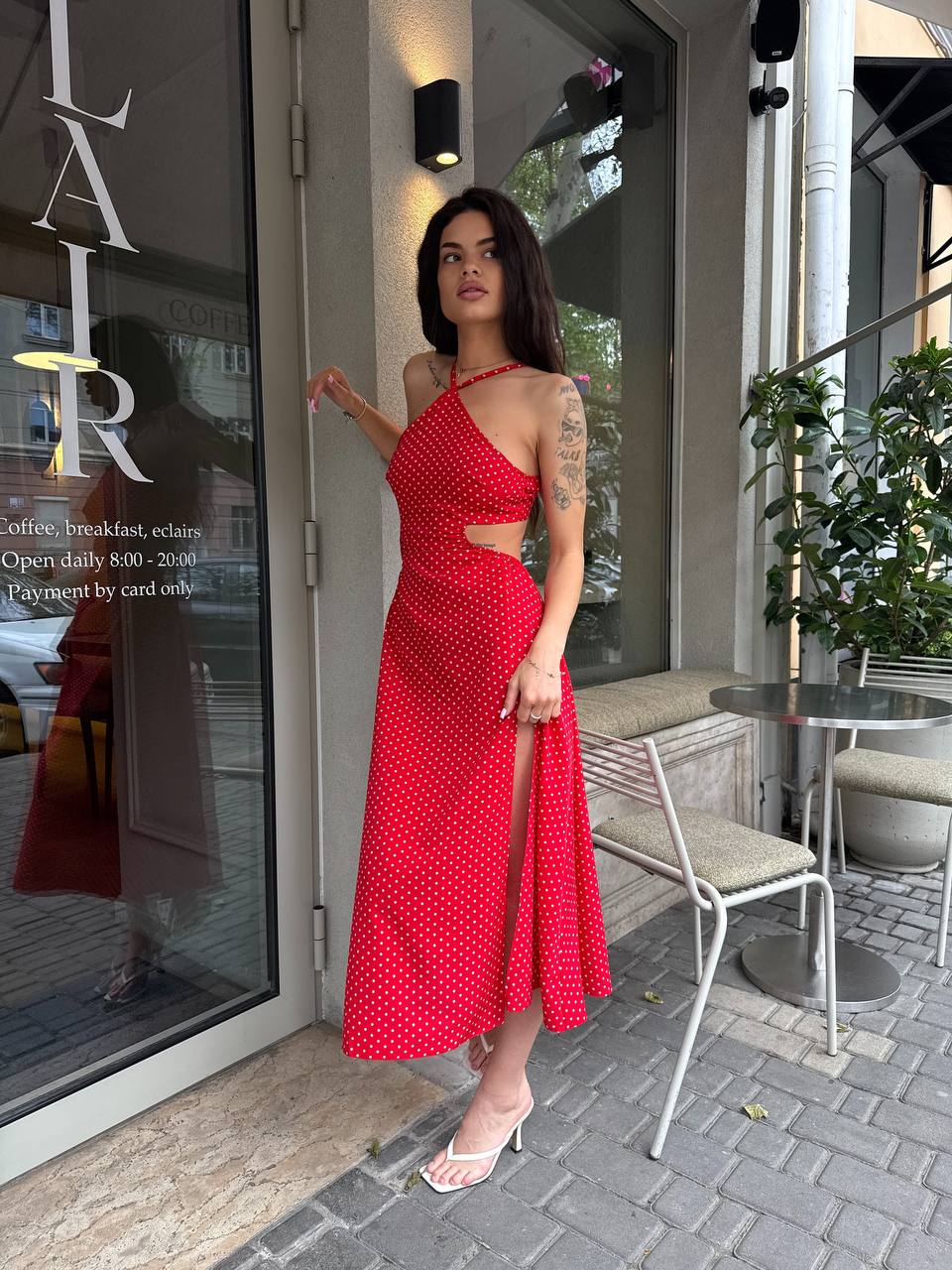 Woman in a red dress standing outside a coffee shop.