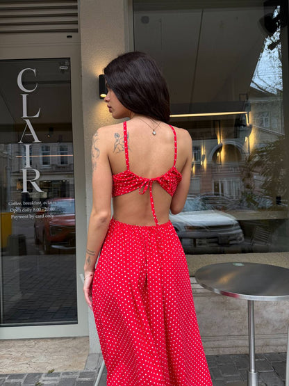 Woman in a red polka dot outfit standing outside a building with 'Clair' on the door.