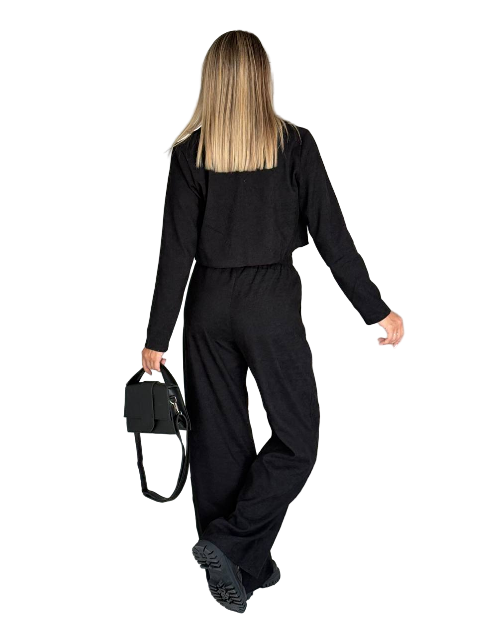 Person wearing a black outfit holding a black bag on a white background