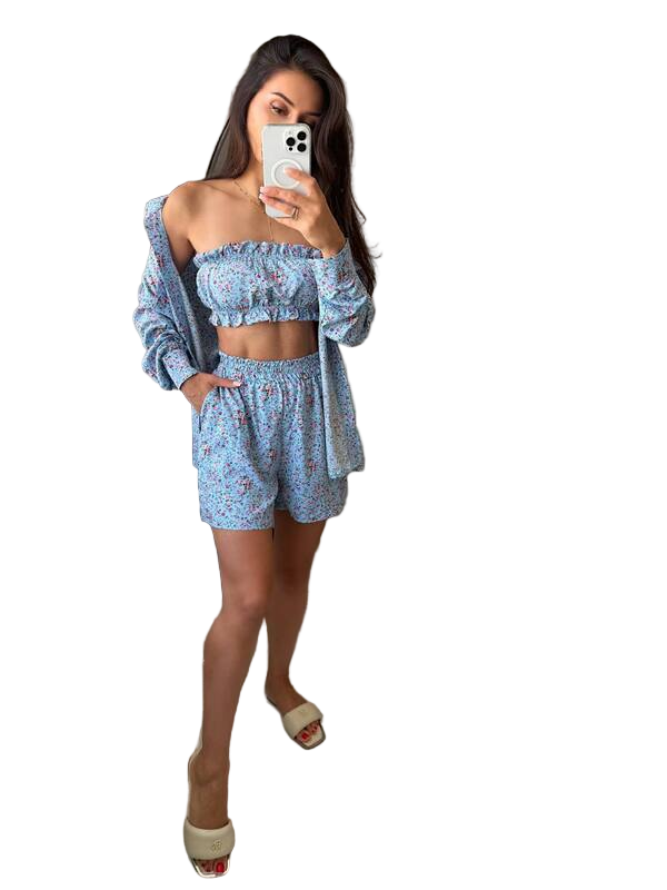 Woman taking a mirror selfie wearing a blue floral outfit on a white background