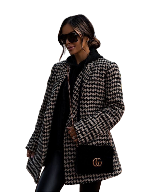 Woman wearing a houndstooth patterned coat with a black handbag featuring a logo on a white background
