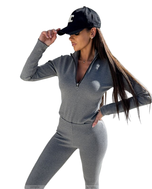 Woman wearing a gray athletic outfit and black cap on a white background