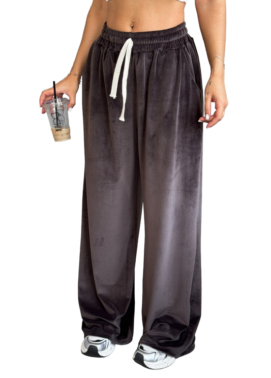 Person wearing dark gray sweatpants with a white drawstring, holding a drink.