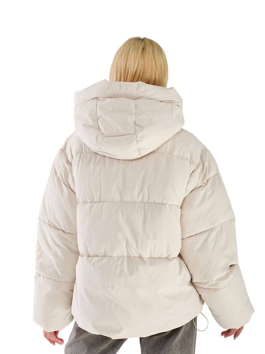 Person wearing a beige puffer jacket on a white background