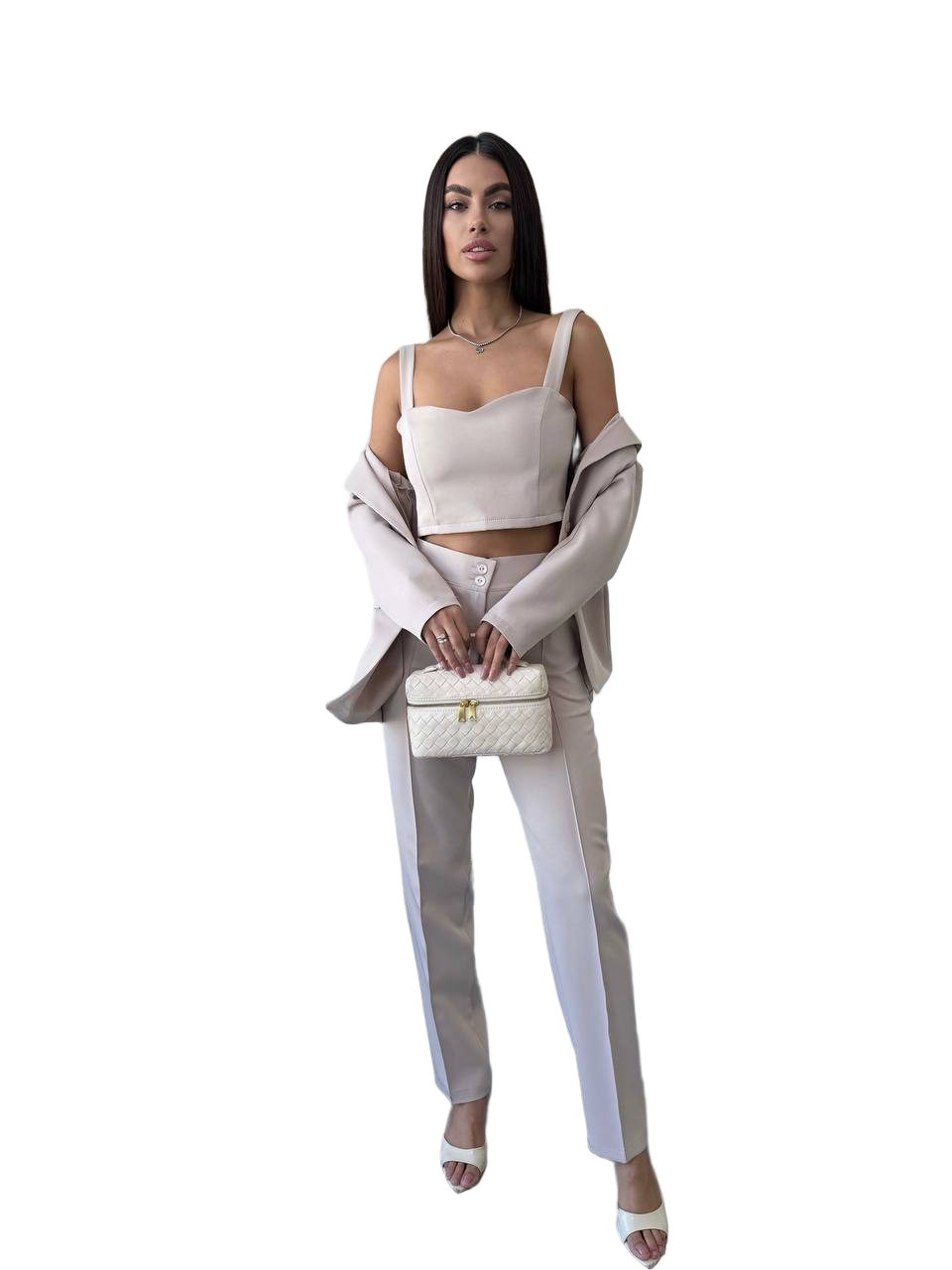 Woman in a stylish outfit with a white top and pants, holding a matching handbag on a white background.