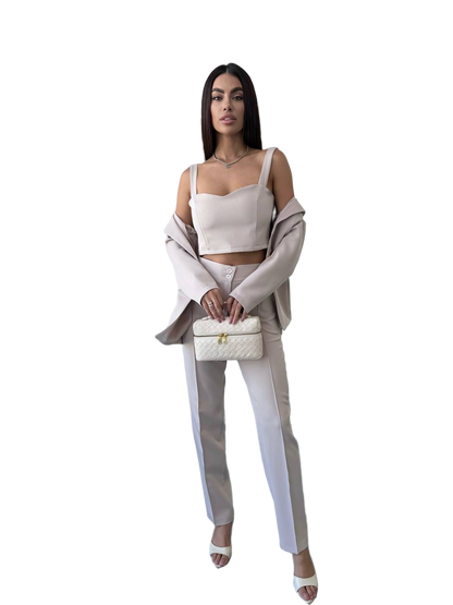 Woman in a stylish outfit with a white top and pants, holding a matching handbag on a white background.