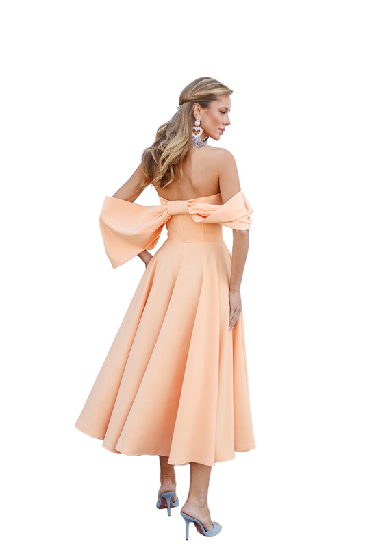 Woman wearing a peach dress with wide sleeves on a white background
