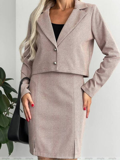 Woman wearing a beige suit with a black handbag on a light gray background