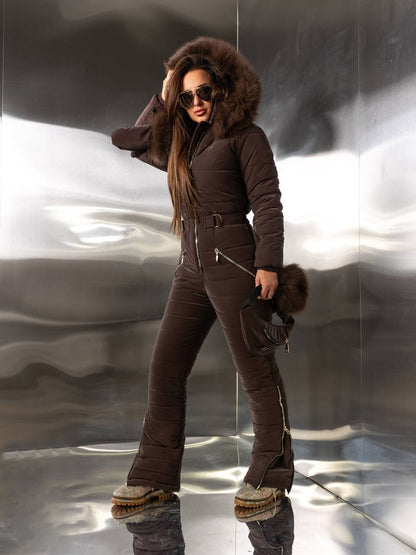 Person wearing a brown snowsuit with fur trim against a reflective metallic background
