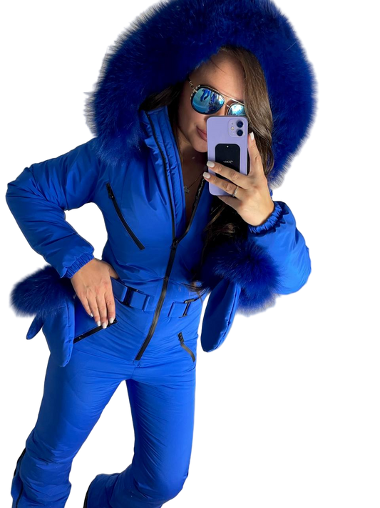 Person wearing a blue snowsuit with a fur-lined hood, taking a selfie.