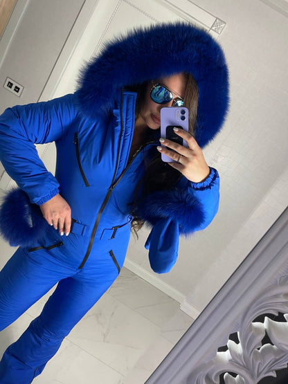 Person wearing a blue snowsuit with a fur-lined hood taking a mirror selfie.